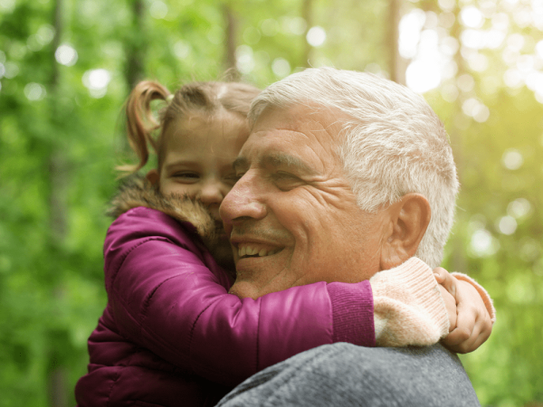grandpa_holding_granddaughter_outside_green_leaves-1000x750-min.png